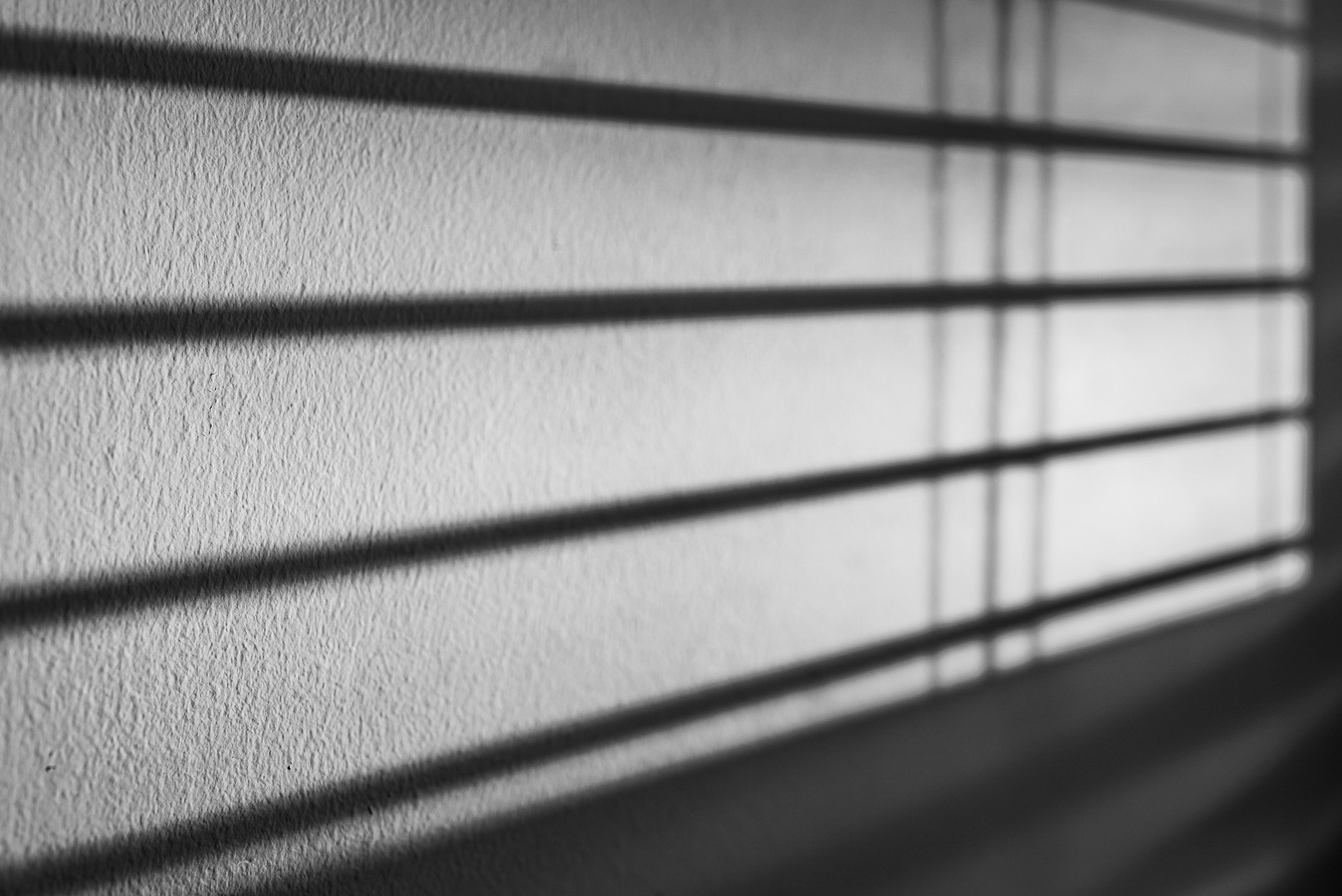 Shadow of venetian blinds caste upon an interior wall